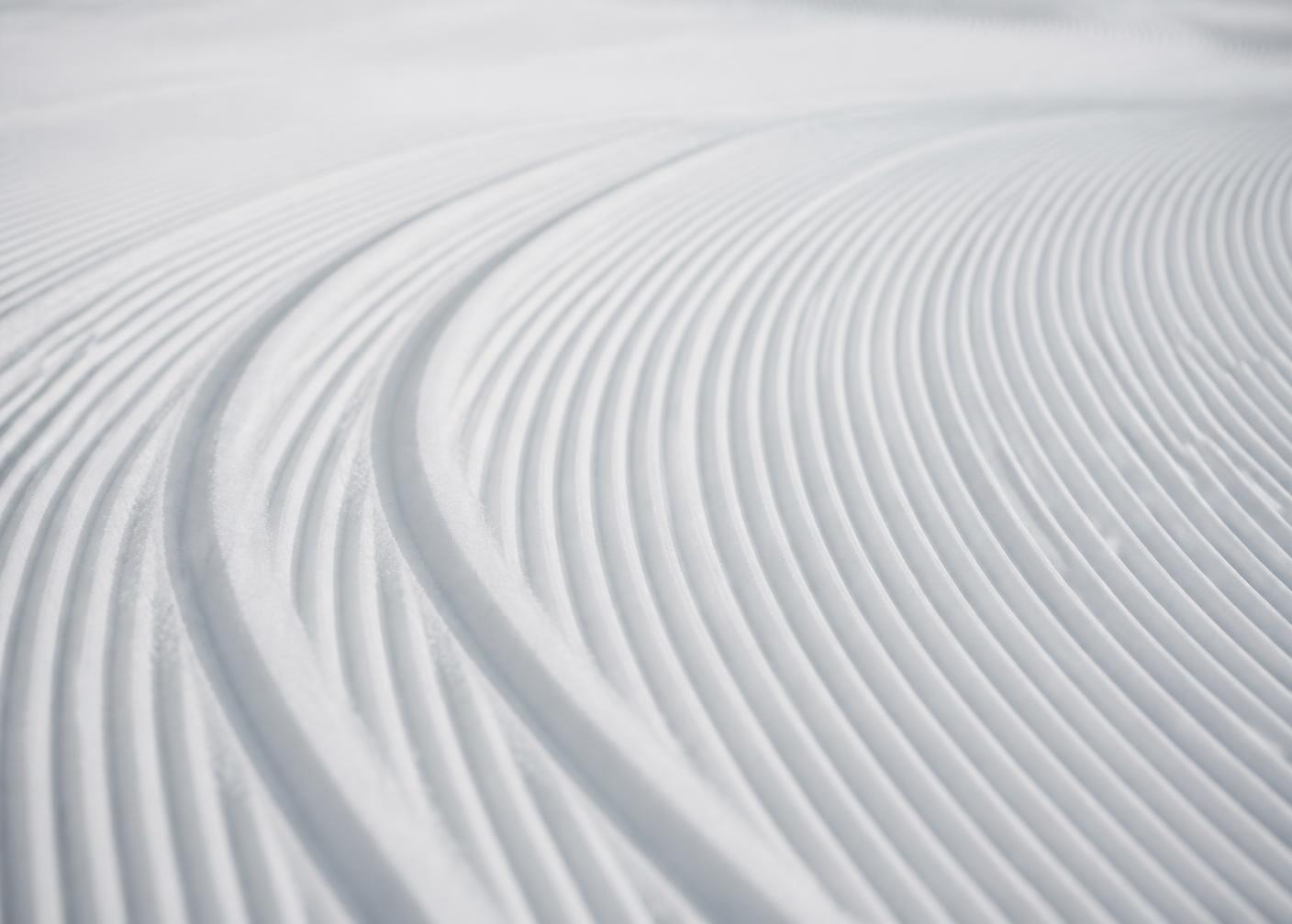 Clean parallel carving tracks on corduroy snow