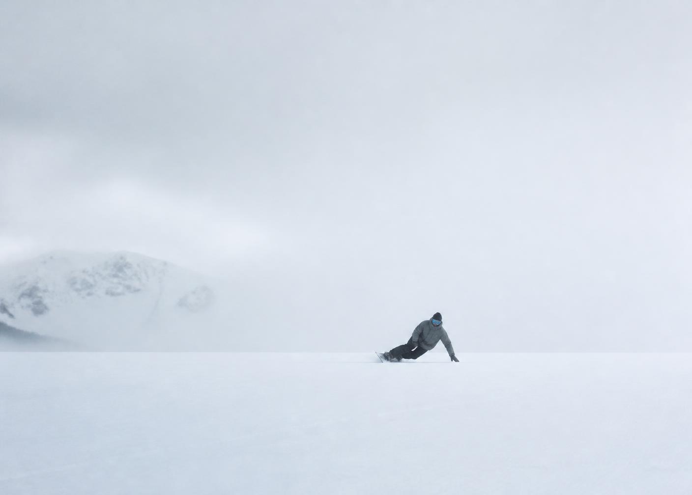 Snowboarder pressing a flatland butter on an empty flat slope